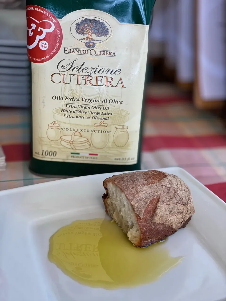 Olivenöl Extra Vergine Selezione Cutrera in der Dose mit Francucci-Etikett, davor hausgebackenes Brot in einer Lache Öl
