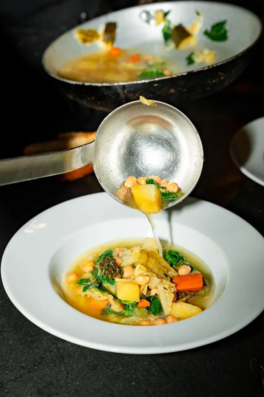 Ribollita di Verdure: vegetable minestrone with chickpeas being ladled into the bowl